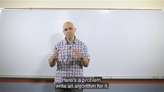 A man in business attire stands in front of a whiteboard filled with numbers, indicating a professional setting.